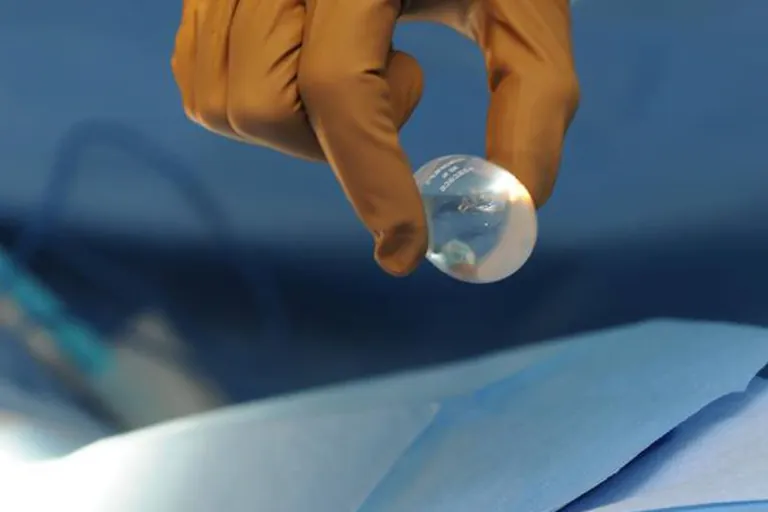 A testicular implant held in a gloved hand
