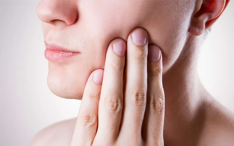 A woman holding the side of her jaw